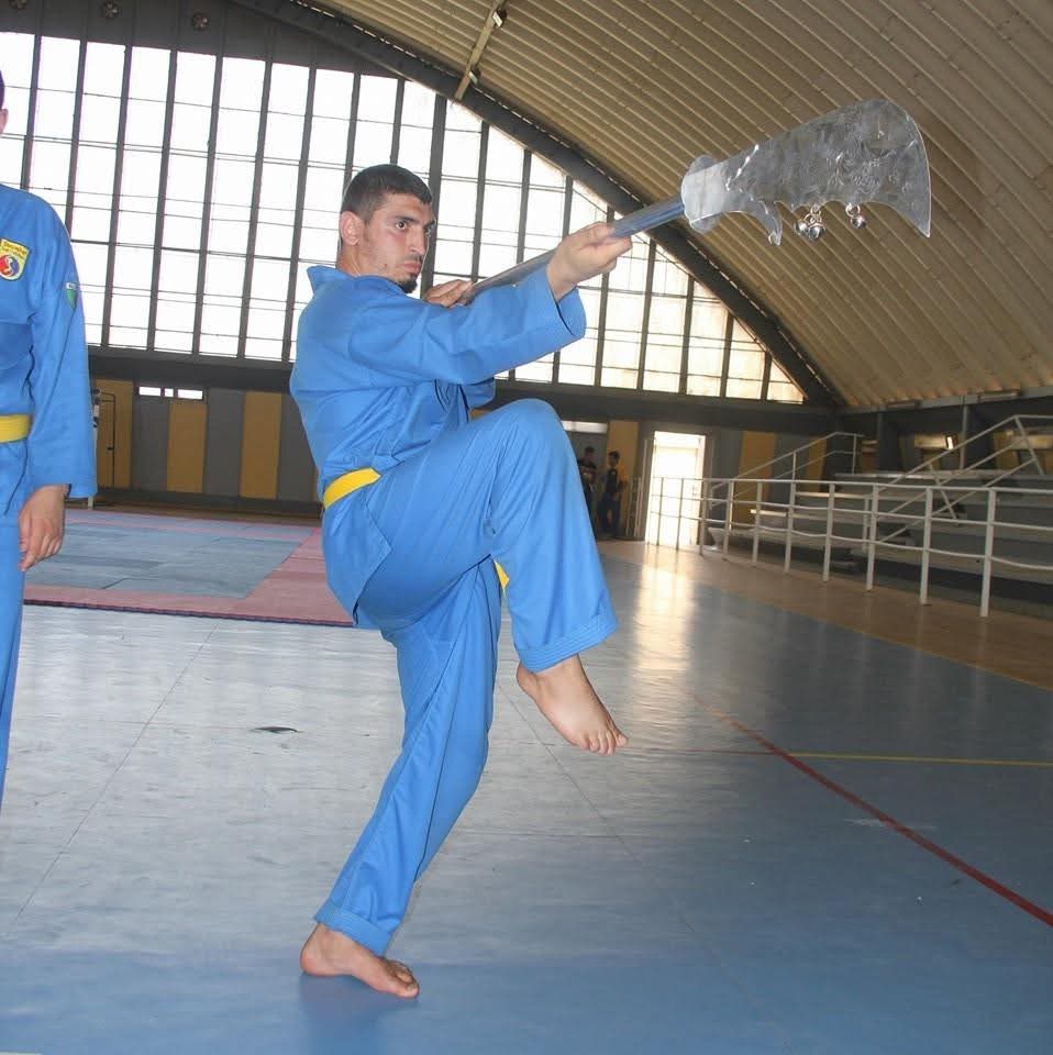 Executing a đại đao (great-blade) weapon form in the dojo