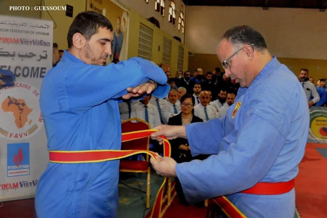 Red-belt promotion ceremony — Master Mohamed tying the belt at the FAVV